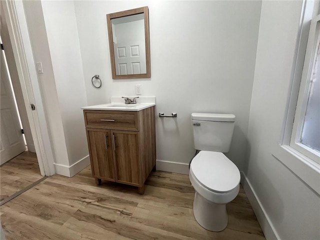 bathroom featuring wood-type flooring, toilet, and vanity