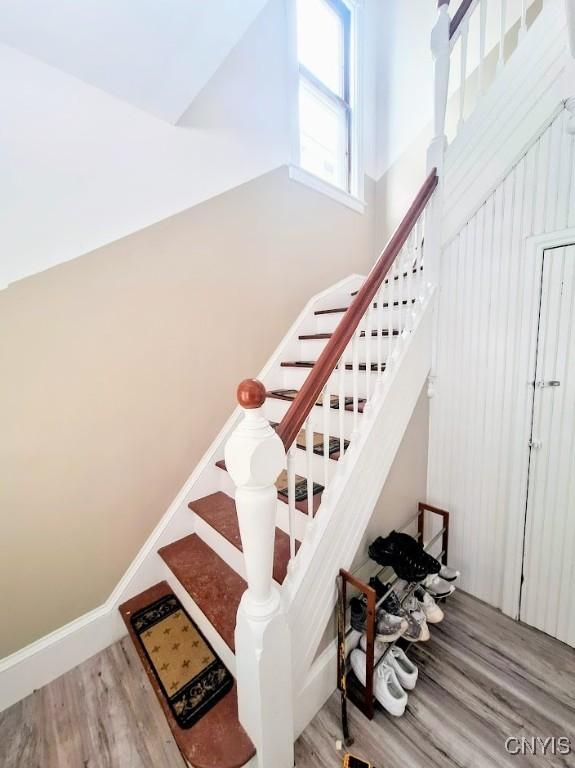 stairs with wood-type flooring and a towering ceiling