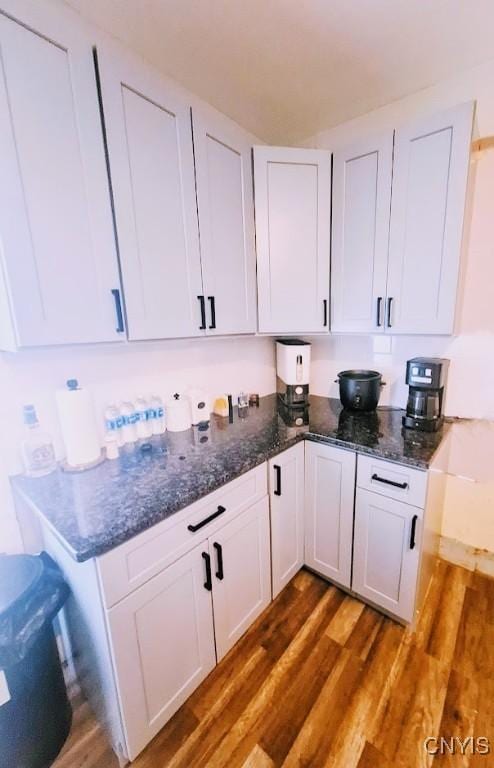 kitchen with dark stone countertops, dark hardwood / wood-style floors, and white cabinets