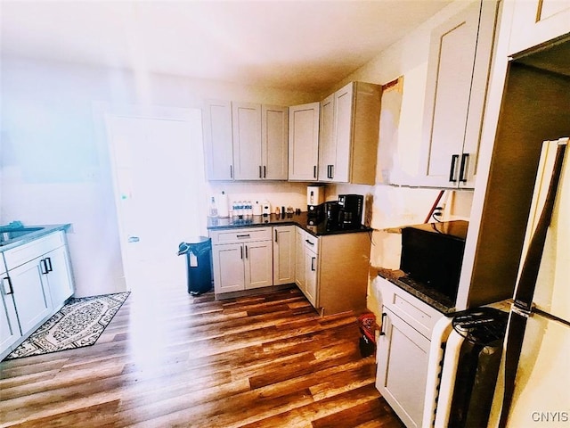 kitchen with white cabinetry, sink, dark hardwood / wood-style flooring, and fridge