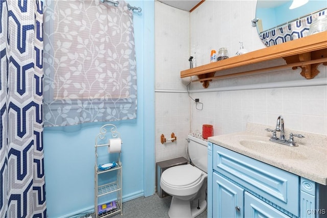 bathroom featuring vanity, toilet, and tile walls