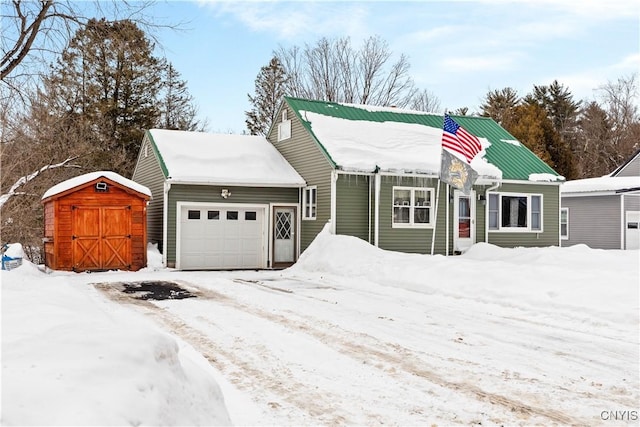 view of front of house with a garage, metal roof, and a storage shed