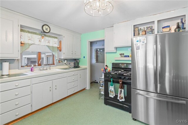 kitchen featuring sink, gas stove, stainless steel fridge, a notable chandelier, and white cabinets