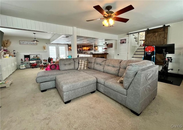 living room with french doors, ceiling fan, a barn door, and light carpet