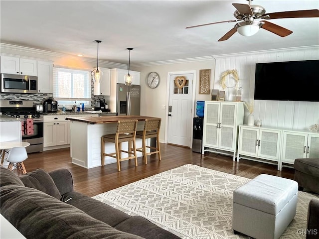 living room with crown molding, ceiling fan, and dark wood-type flooring