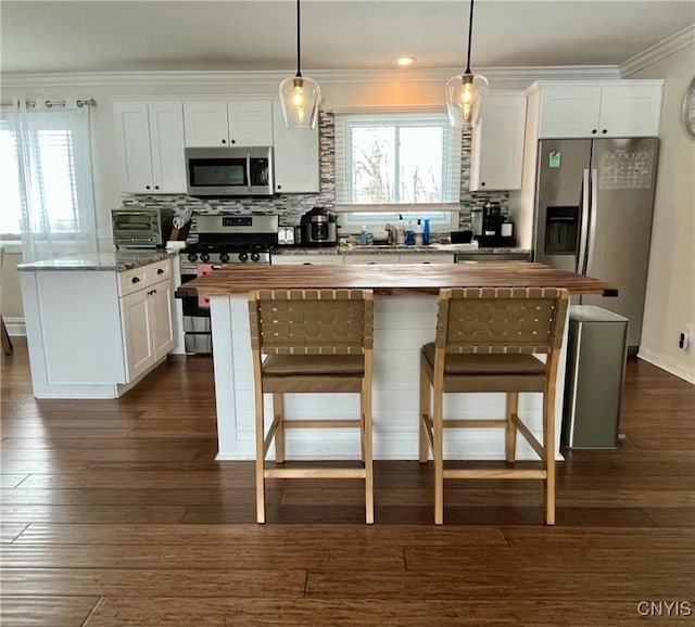 kitchen featuring stainless steel appliances, dark hardwood / wood-style floors, a center island, white cabinets, and decorative light fixtures