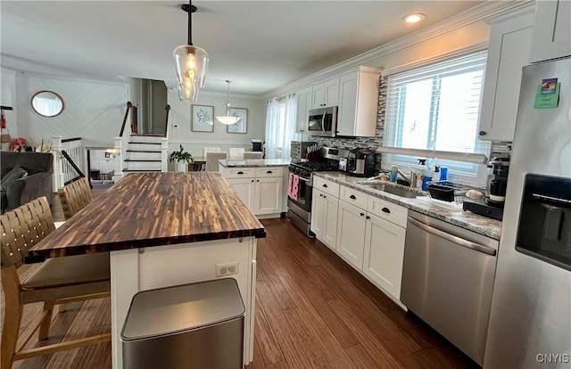 kitchen featuring a kitchen island, appliances with stainless steel finishes, sink, white cabinets, and wooden counters