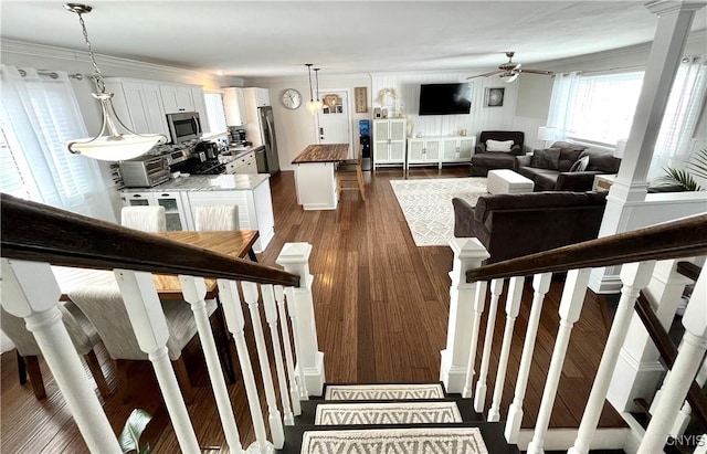 staircase with hardwood / wood-style flooring, ornamental molding, ceiling fan, and decorative columns