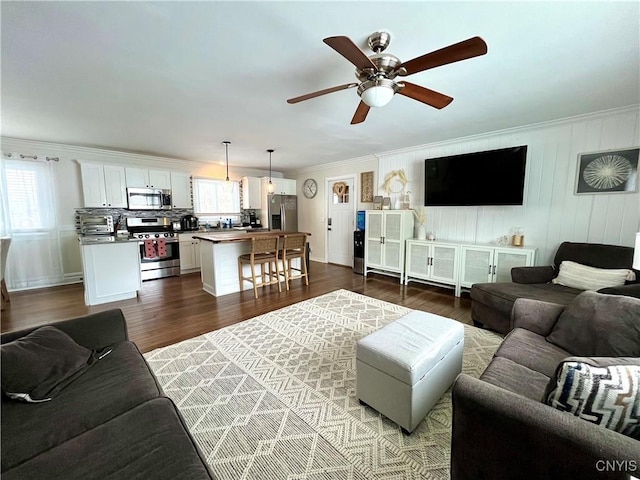 living room featuring crown molding, ceiling fan, and dark hardwood / wood-style flooring