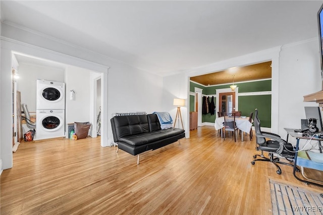 living room featuring hardwood / wood-style flooring, ornamental molding, and stacked washer and clothes dryer