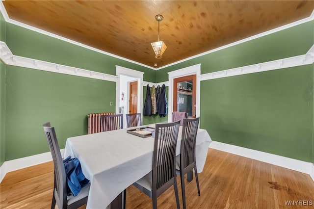 dining area with wood-type flooring, ornamental molding, and wood ceiling