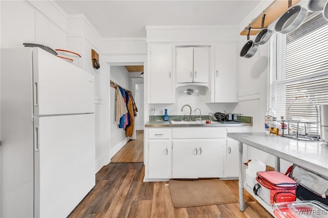 kitchen with dark wood-type flooring, sink, crown molding, white refrigerator, and white cabinets