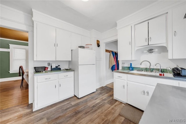 kitchen featuring sink, white cabinetry, crown molding, wood-type flooring, and white refrigerator