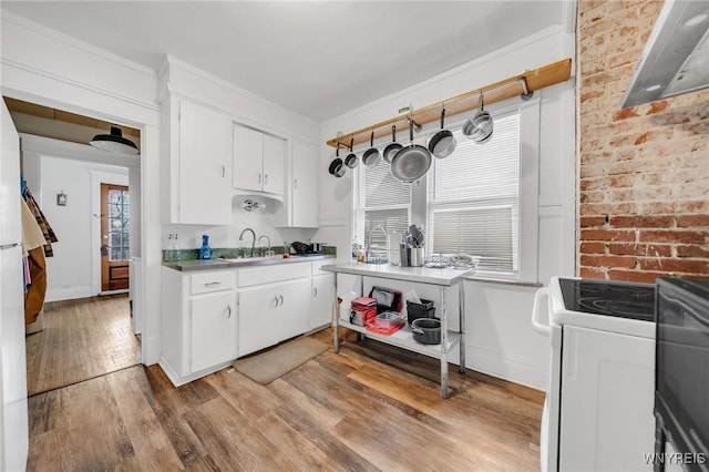 kitchen with white cabinetry, brick wall, washer / clothes dryer, and light hardwood / wood-style floors