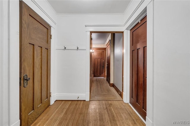 corridor with ornamental molding and light hardwood / wood-style floors