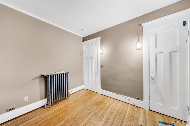 unfurnished room with hardwood / wood-style flooring, crown molding, and radiator heating unit