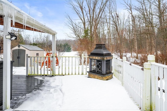 snow covered patio with a wooden deck and a storage shed