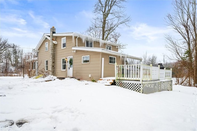 snow covered house featuring a wooden deck