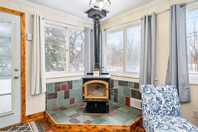 living area with ornamental molding and a wood stove