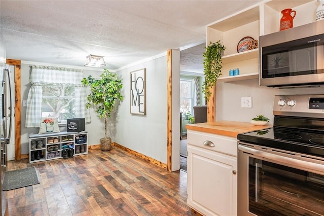 kitchen with butcher block counters, a textured ceiling, appliances with stainless steel finishes, hardwood / wood-style floors, and white cabinets