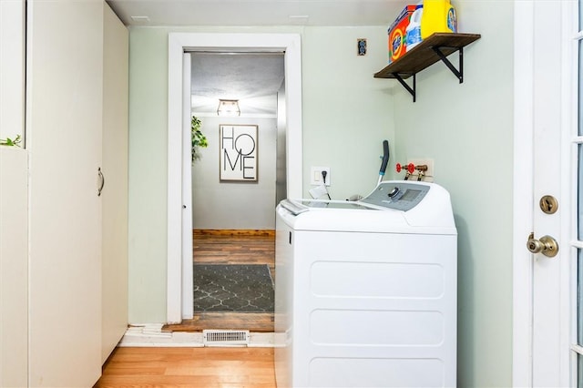 laundry room with washing machine and dryer and light hardwood / wood-style floors