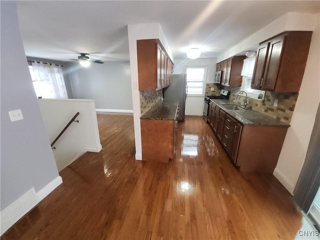 kitchen with hardwood / wood-style floors, tasteful backsplash, sink, dark stone countertops, and stainless steel appliances