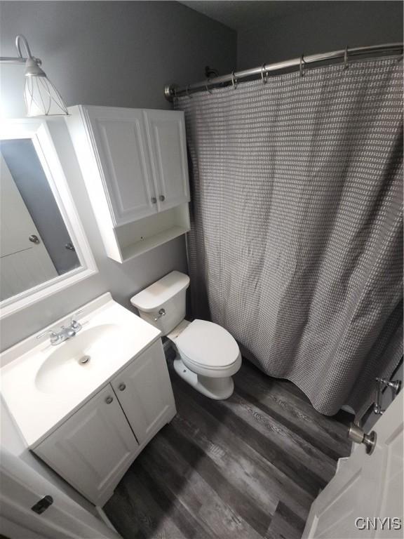 bathroom with vanity, hardwood / wood-style floors, curtained shower, and toilet