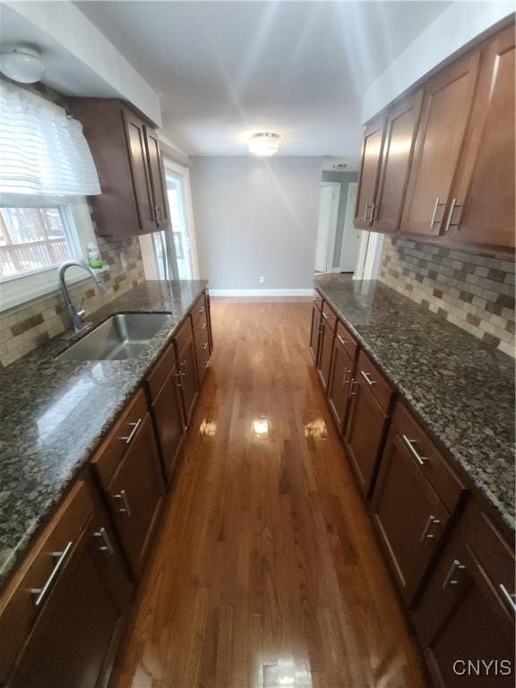 kitchen with sink, dark hardwood / wood-style floors, dark stone counters, and decorative backsplash