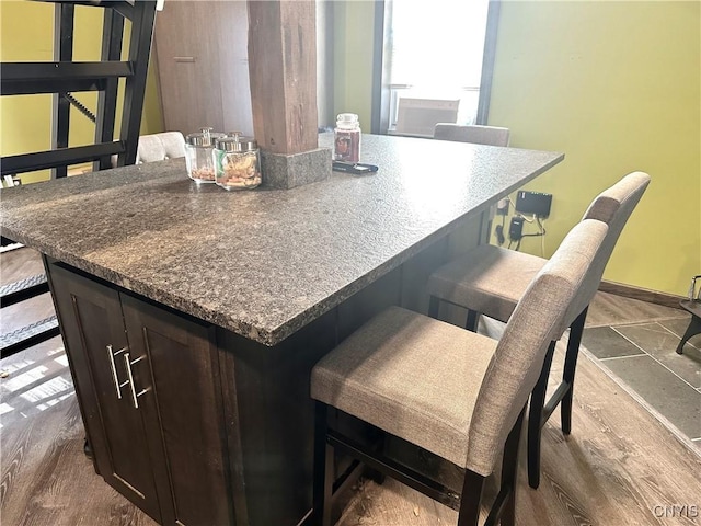 kitchen featuring dark brown cabinets, a breakfast bar, wood-type flooring, and a kitchen island