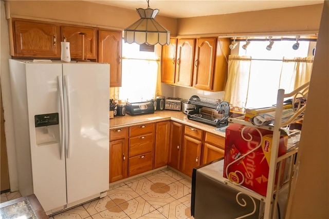 kitchen with hanging light fixtures and white fridge with ice dispenser