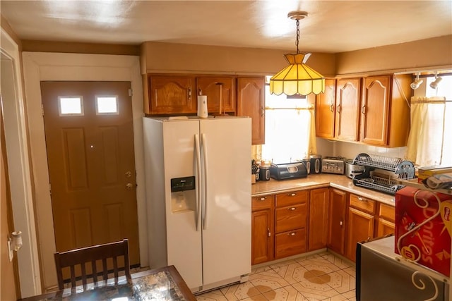 kitchen featuring white fridge with ice dispenser and decorative light fixtures