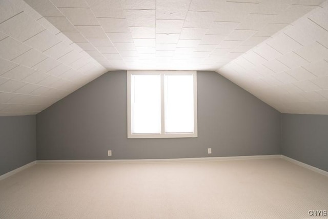 additional living space featuring lofted ceiling and carpet