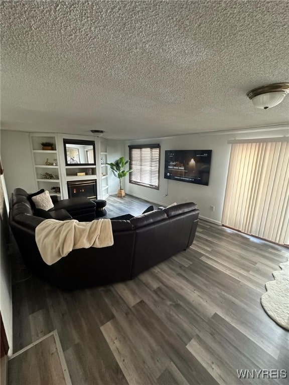 living room with hardwood / wood-style floors, a textured ceiling, and built in shelves