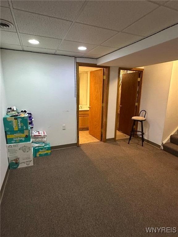 interior space featuring a paneled ceiling and carpet flooring