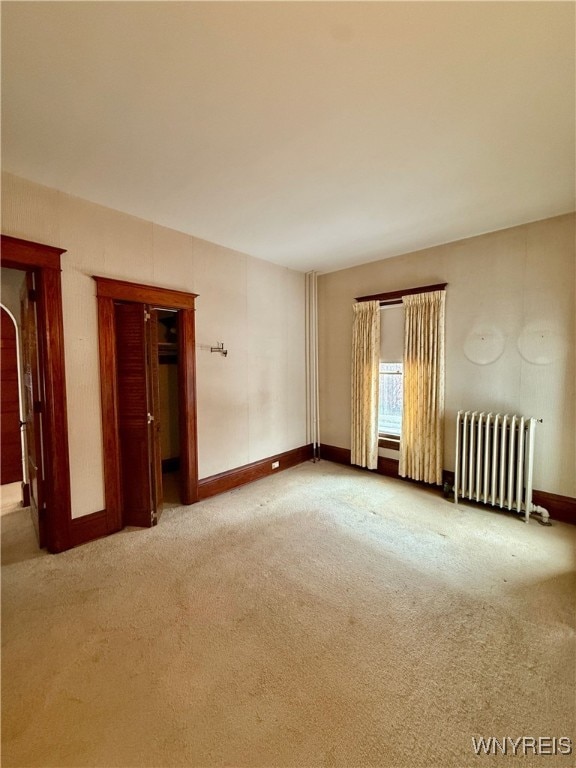 spare room with light colored carpet and radiator heating unit