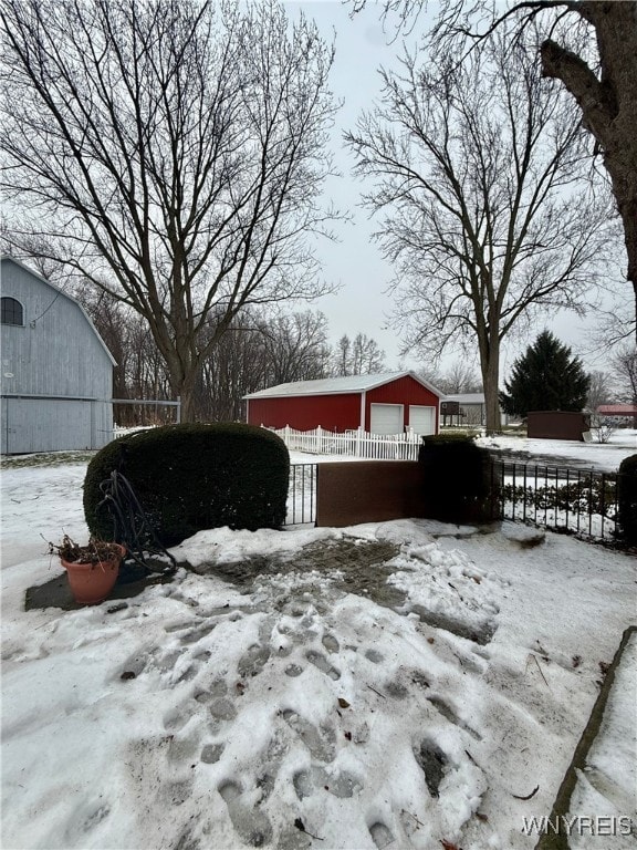 snowy yard with a garage and an outdoor structure