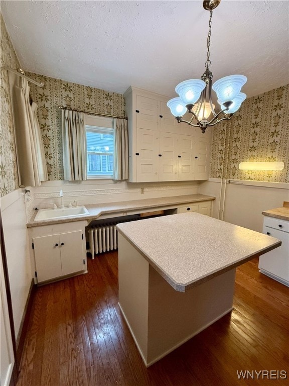 kitchen featuring sink, dark wood-type flooring, white cabinetry, a textured ceiling, and decorative light fixtures