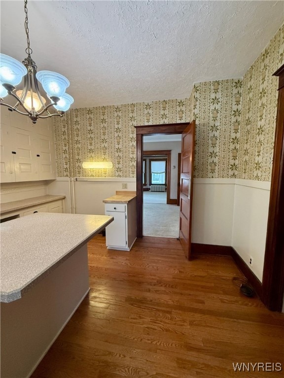 kitchen featuring pendant lighting, a textured ceiling, dark hardwood / wood-style flooring, and white cabinets