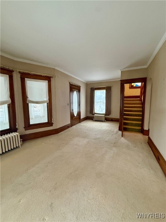 unfurnished living room with ornamental molding, radiator heating unit, and carpet floors