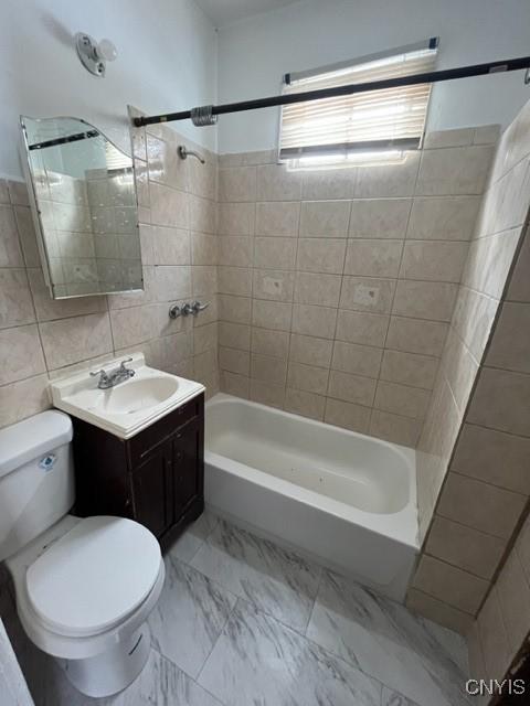 full bathroom with tiled shower / bath combo, vanity, tile walls, and toilet