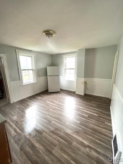 1218 City St, Utica, NY 13502 - spare room with wood finished floors, visible vents, and wainscoting