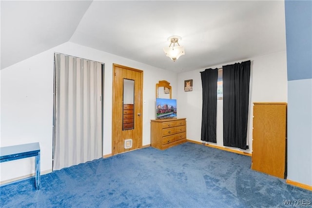 unfurnished bedroom with vaulted ceiling and dark colored carpet