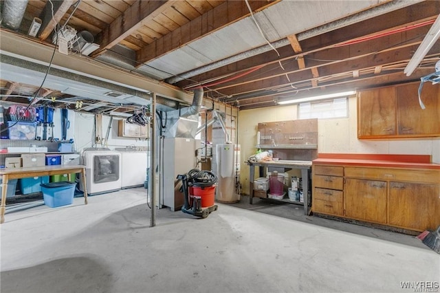 basement with gas water heater, washer and clothes dryer, and a workshop area