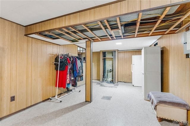 basement with white refrigerator and wood walls