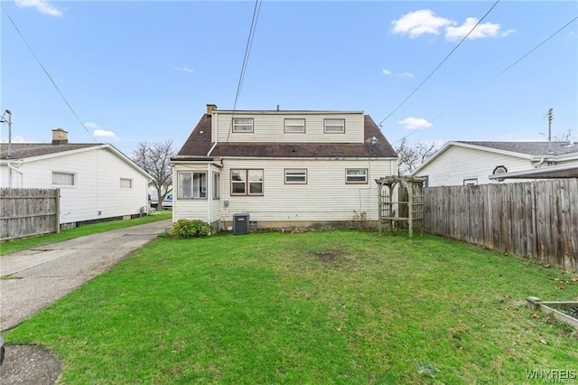 back of property featuring central AC unit and a lawn