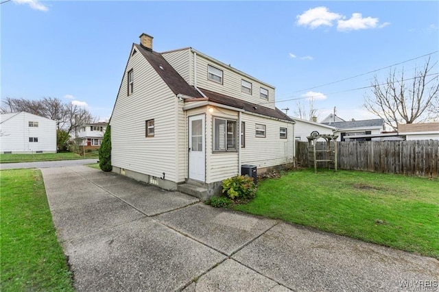 rear view of house with central AC, a patio, and a lawn