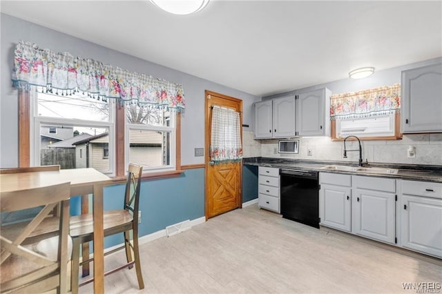 kitchen with gray cabinetry, black dishwasher, sink, and backsplash