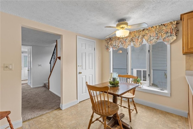 dining room with a textured ceiling, light colored carpet, and ceiling fan