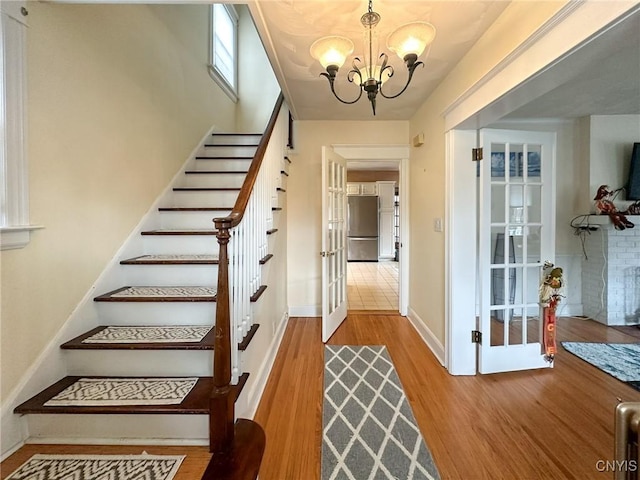 stairway featuring hardwood / wood-style flooring, a notable chandelier, and french doors