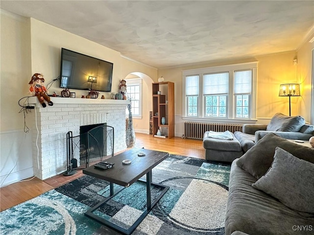 living room featuring radiator heating unit, a fireplace, and hardwood / wood-style floors